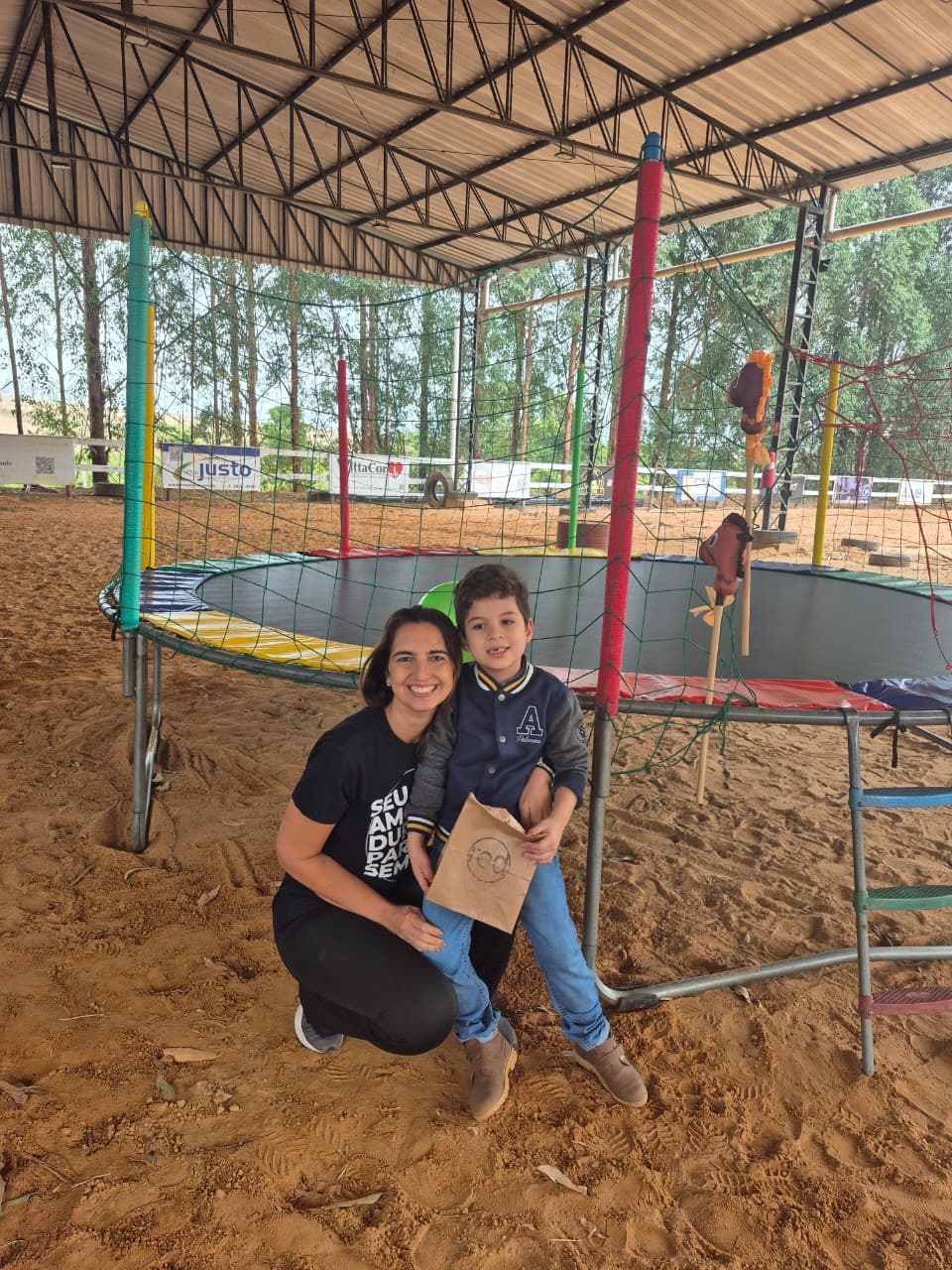 Voluntária ao lado de uma criança em um espaço de equoterapia
