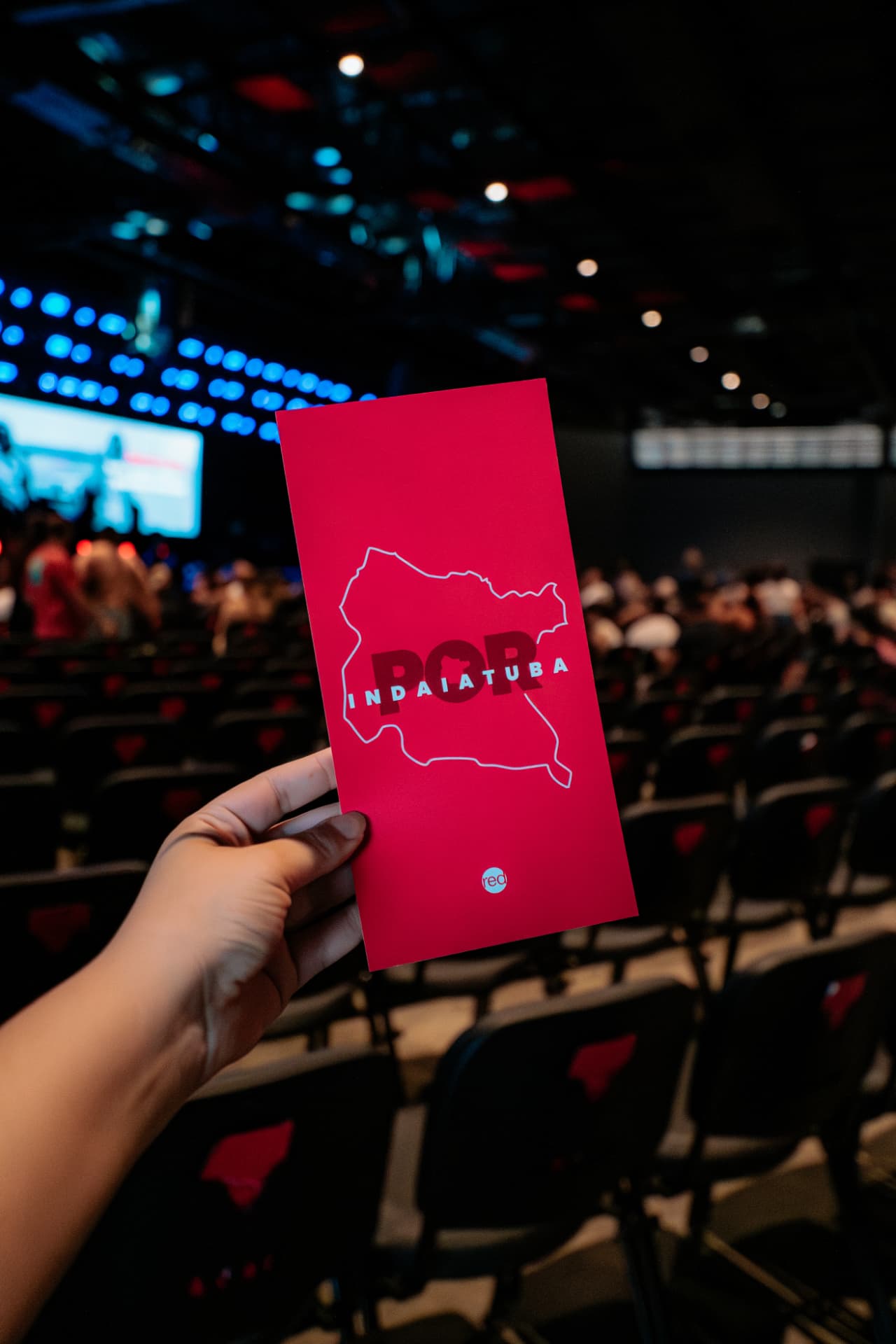 Cartão vermelho Por Indaiatuba com o mapa da cidade erguido durante um culto