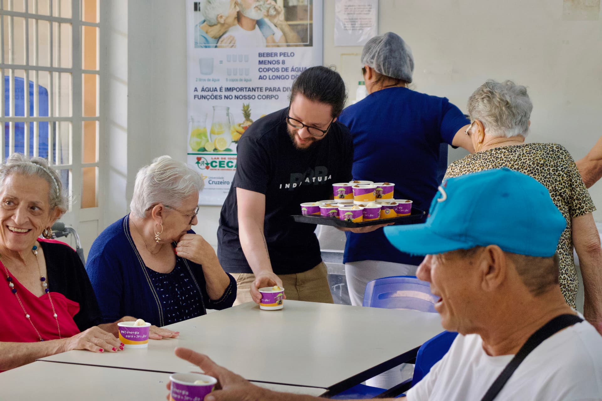 Voluntário da Red servindo sobremesa a pessoas idosas em uma instituição